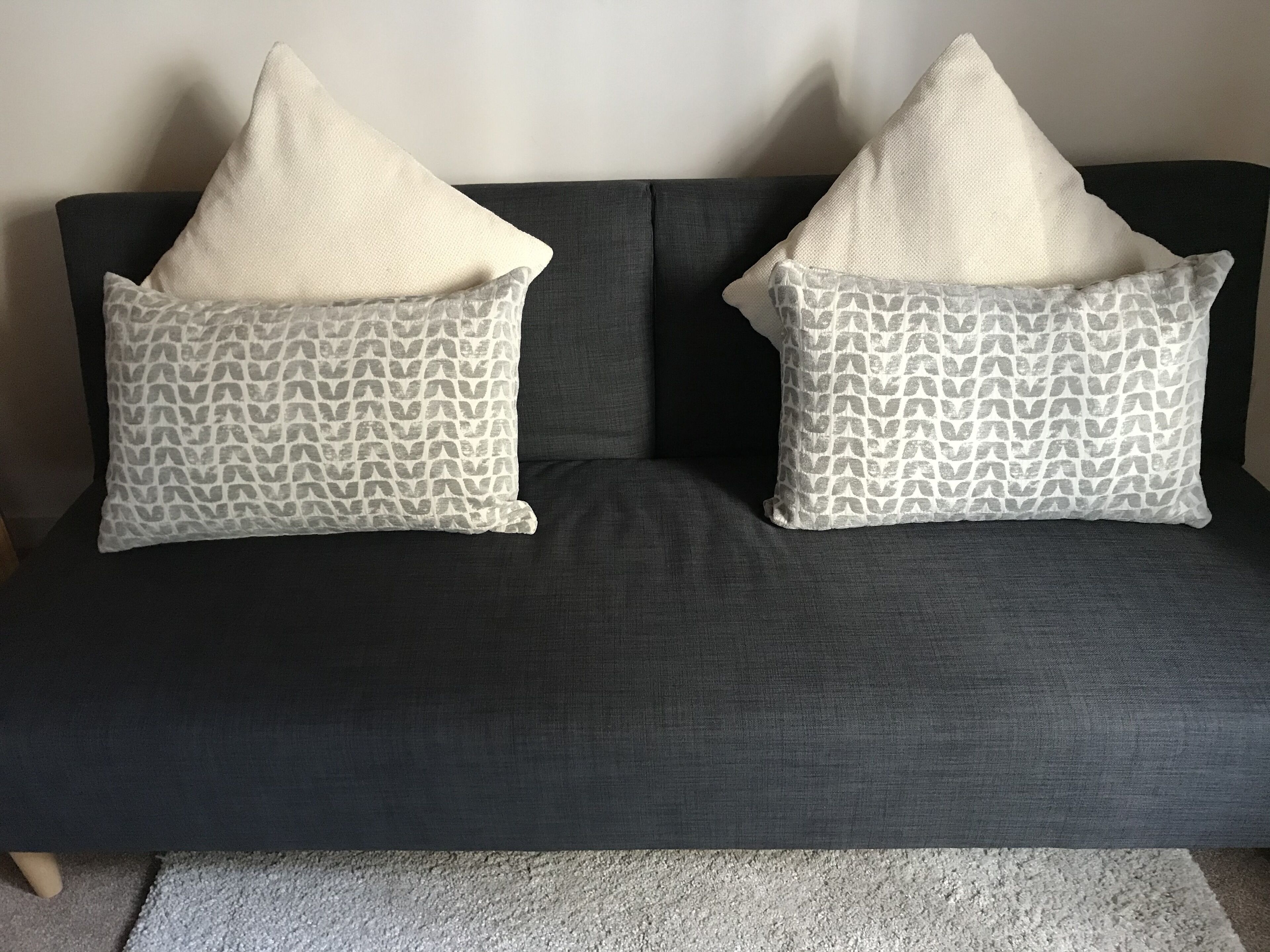 Un canapé gris foncé agrémenté de deux coussins à motifs.