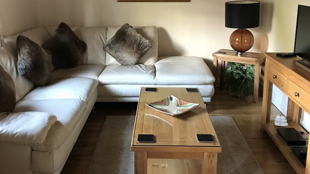 A living room with a white sofa, a wooden coffee table, a lamp, and a painting on the wall. - Kilchurn Suites (Dalmally)