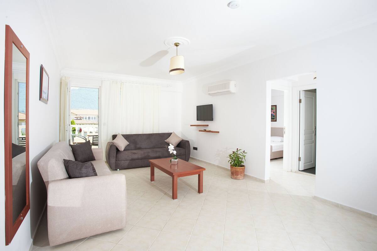 A modern living room with a sofa, a coffee table, and a TV mounted on the wall.
