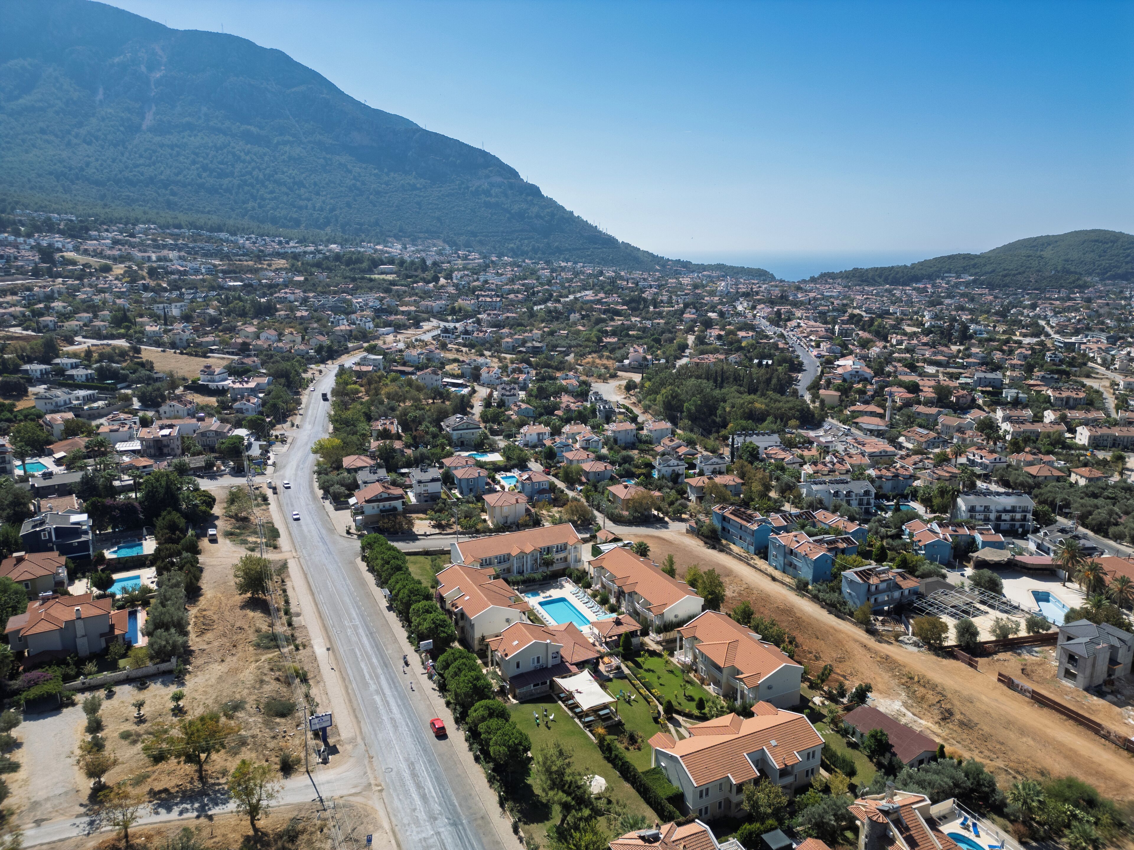 Vista aérea de una zona residencial con casas, caminos y una montaña al fondo.