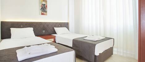 A hotel room with two beds, a nightstand, a painting, and a window with curtains.
