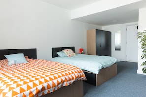 Ein modernes Schlafzimmer mit zwei Betten, einem Kleiderschrank und einem Spiegel.