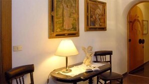 A hallway with a lamp, two chairs, and two paintings on the wall. - Hotel Mair am Turm (Tirolo)