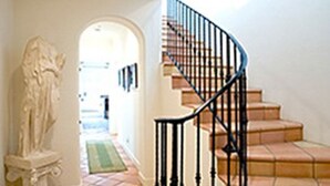 A staircase with beige steps and black balusters, leading to a landing with a green patterned runner. - Experience West Beach living, just steps away from Santa Barbara Harbor (Santa Barbara)
