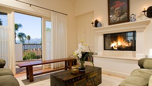 A living room with a fireplace, a bench, a coffee table with a decorative box, and a view of the outdoors. - Experience West Beach living, just steps away from Santa Barbara Harbor (Santa Barbara)