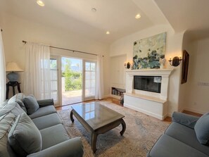 A living room with a sofa, coffee table, fireplace, and a painting above it. - Experience West Beach living, just steps away from Santa Barbara Harbor (Santa Barbara)
