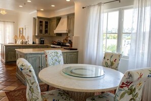 A kitchen with a central island, a round dining table, and floral-patterned chairs. - Experience West Beach living, just steps away from Santa Barbara Harbor (Santa Barbara)