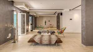 A modern living room with a sofa, a colorful chair, and a dining area with a table and chairs. - Aurelia Vatican Suites (Rome)