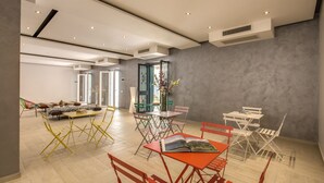A spacious living area with a large sofa, a dining table with chairs, and a bookshelf. - Aurelia Vatican Suites (Rome)
