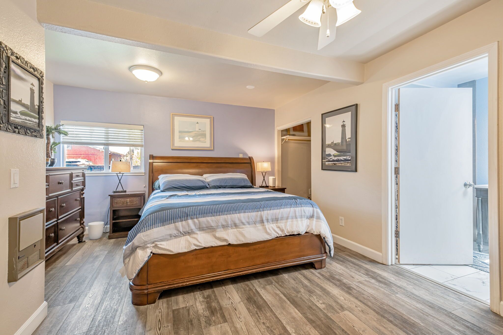 A bedroom with a wooden bed, a nightstand, a dresser, and a window with blinds.