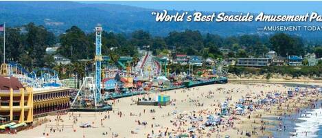 Un parc d’attractions situé en bord de mer, avec une grande roue, des montagnes russes et une promenade en bord de plage.