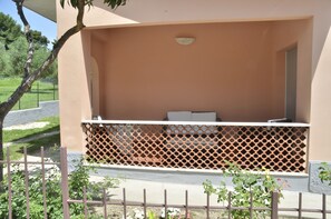 A covered outdoor seating area with a lattice fence, a bench, and a small table. - Operà B&B (Sirolo)