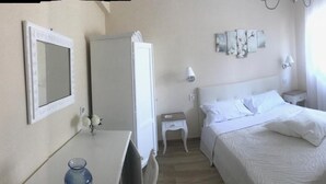 Una habitación de hotel con cama, mesita de noche, lámpara y una obra de arte en la pared.