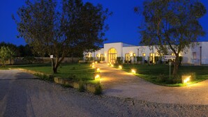 Un edificio moderno con recepción, rodeado por un sendero bien iluminado y vegetación.
