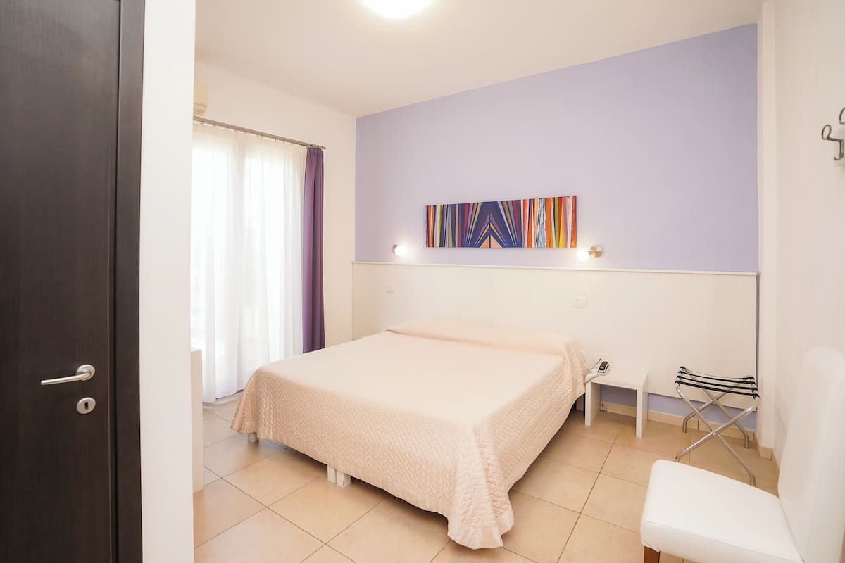 Une chambre à coucher comprenant un lit, une chaise, un banc et un porte-serviettes fixé au mur.