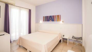 Habitación de hotel con cama, escritorio, silla, una mesita y una obra de arte en la pared.