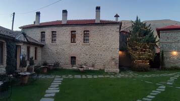 A stone building with a red-tiled roof, a small garden with a Christmas tree, and outdoor seating.