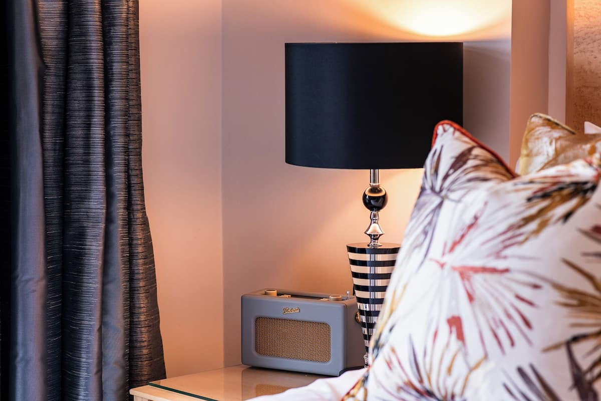 Een kamer met een radio, een lamp en een kussen met een patroon.