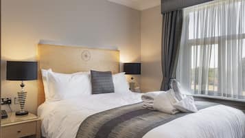 Une chambre d’hôtel avec un lit bien fait, deux lampes de chevet, une table de chevet avec une lampe, une fenêtre avec des rideaux et une vue sur l’extérieur.