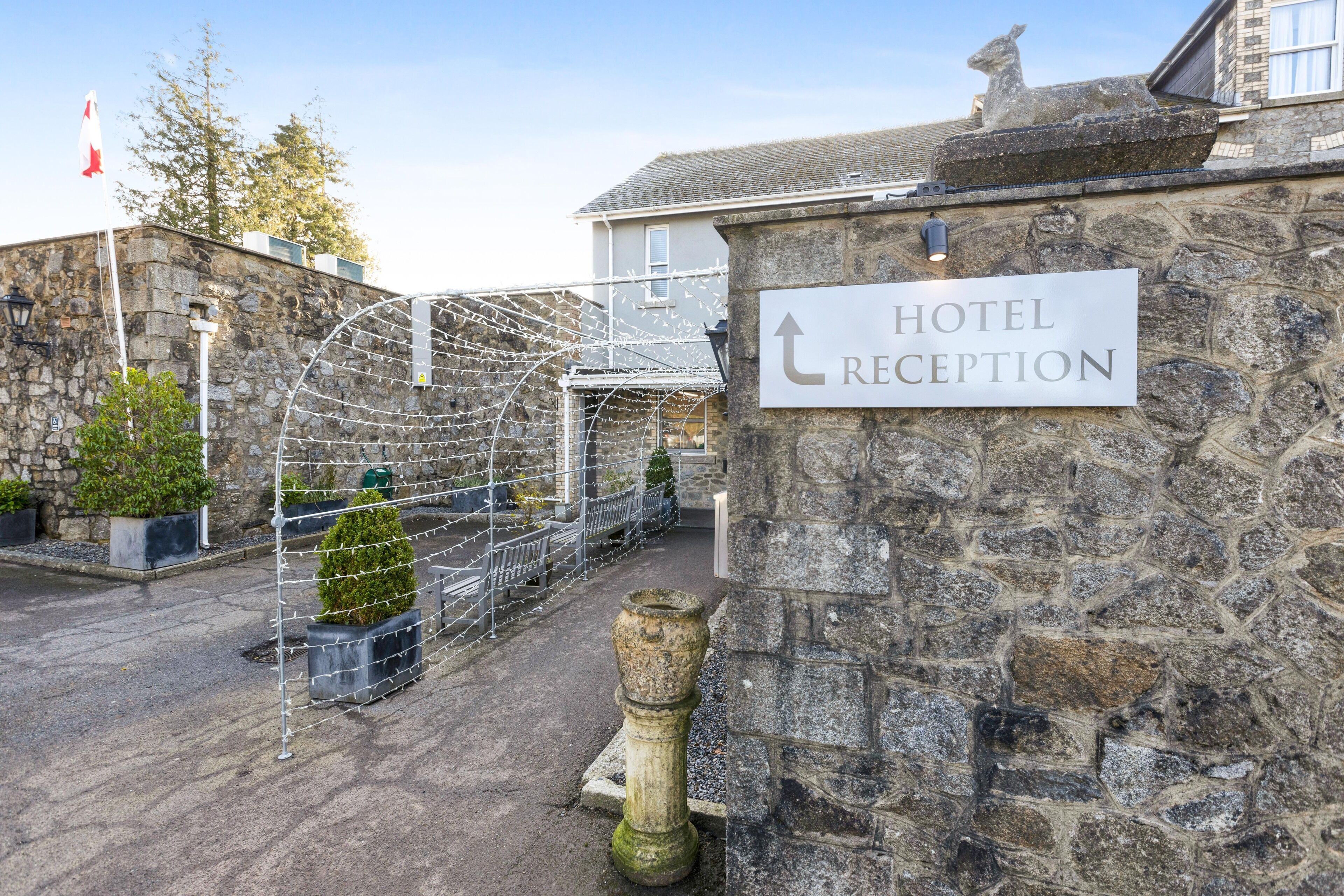 A stone wall with a sign indicating the hotel reception.