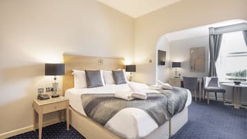 Una habitación de hotel con una cama grande, mesitas de noche con lámparas, un escritorio y una silla.
