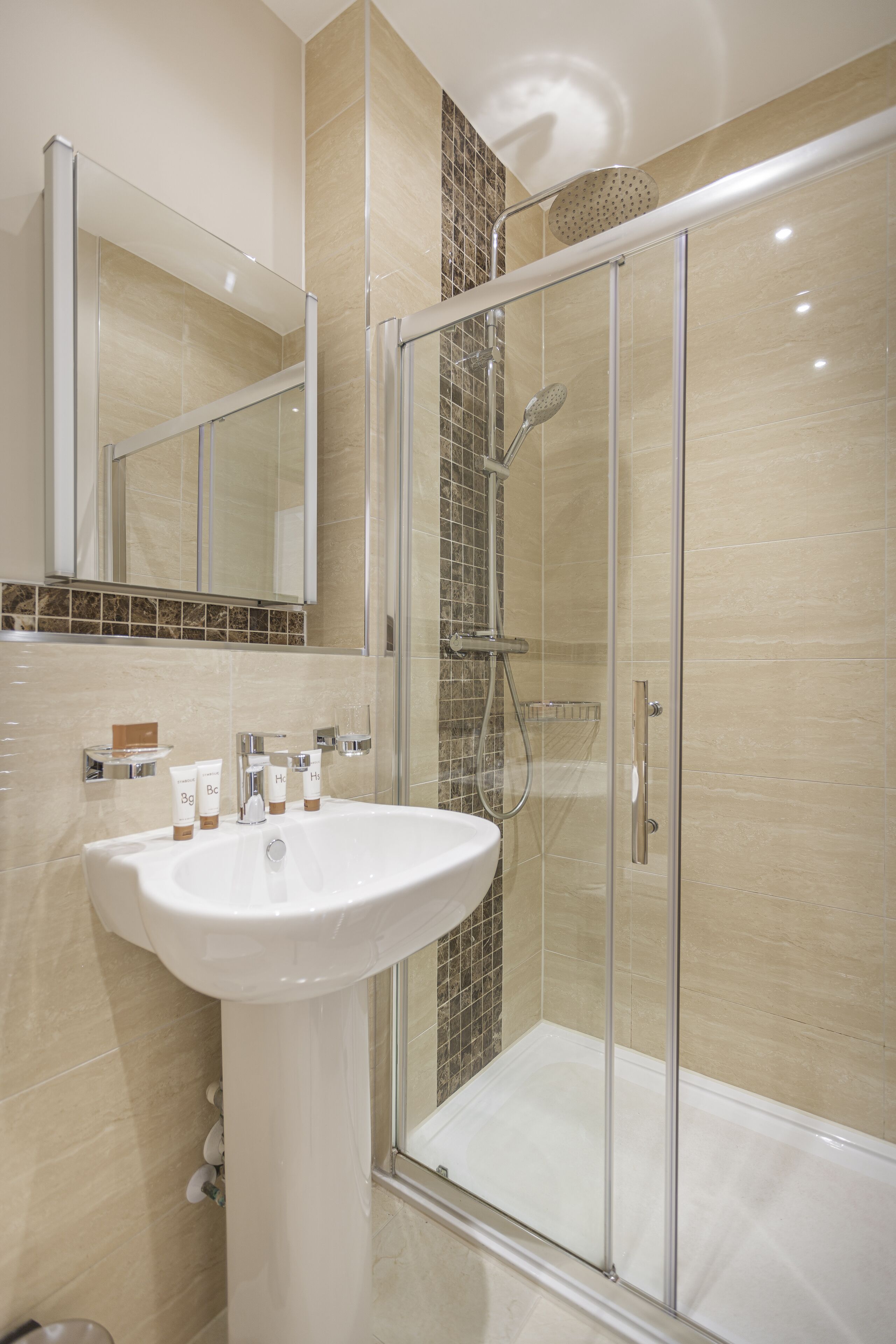 A modern bathroom with a glass-enclosed shower, a white sink, and a mirror above it.