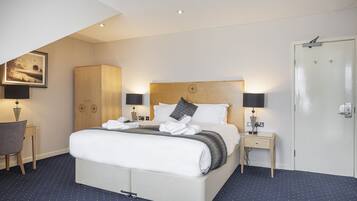 Una habitación de hotel con una cama grande, dos mesitas de noche, un armario y una puerta.