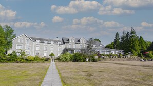 Un grand bâtiment en pierre, doté de nombreuses fenêtres et d’une entrée centrale.