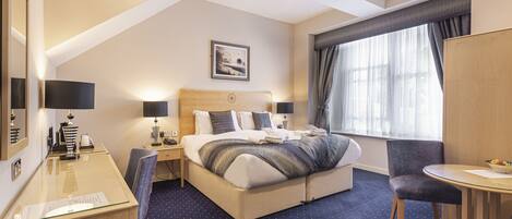 Una habitación de hotel con cama, escritorio, silla y mesa de comedor.
