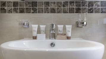 A bathroom sink with toiletries and a glass soap dish.