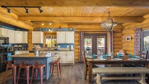 Ein Holzblockhaus-Interieur mit Küche, Essbereich und Bar.