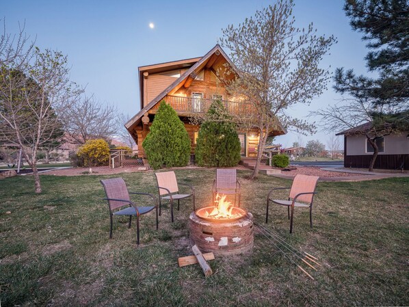 Une cabane en rondins avec un foyer et des sièges d’extérieur.