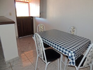 A small dining area with a checkered tablecloth, white chairs with floral patterns, and a tiled floor. - Nossa Casa em Jeri (Jijoca de Jericoacoara)