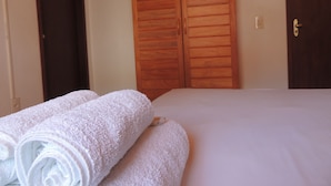 A bedroom with a bed, two wooden wardrobes, and rolled towels. - Nossa Casa em Jeri (Jijoca de Jericoacoara)