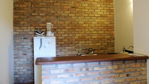 A kitchen with a brick wall, a countertop, and a refrigerator. - Nossa Casa em Jeri (Jijoca de Jericoacoara)