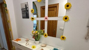 Un bagno con un mobile lavabo bianco, uno specchio e un lavandino a parete.