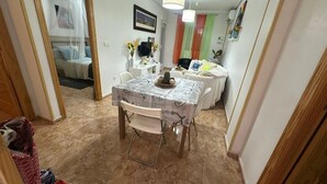 Zona pranzo con tavolo, sedie, lampadario e vista su una camera da letto.