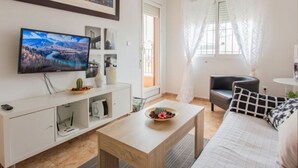 Un soggiorno con TV, divano, tavolino e un letto.