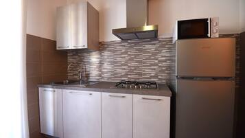 Een moderne keuken met roestvrijstalen apparatuur, een betegelde spatwand en witte keukenkastjes.