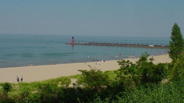 A beach with a pier and a lighthouse.