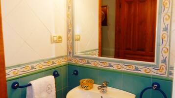 Un baño con un lavamanos blanco, aros para toallas azules y un espejo con detalles de azulejos decorativos.