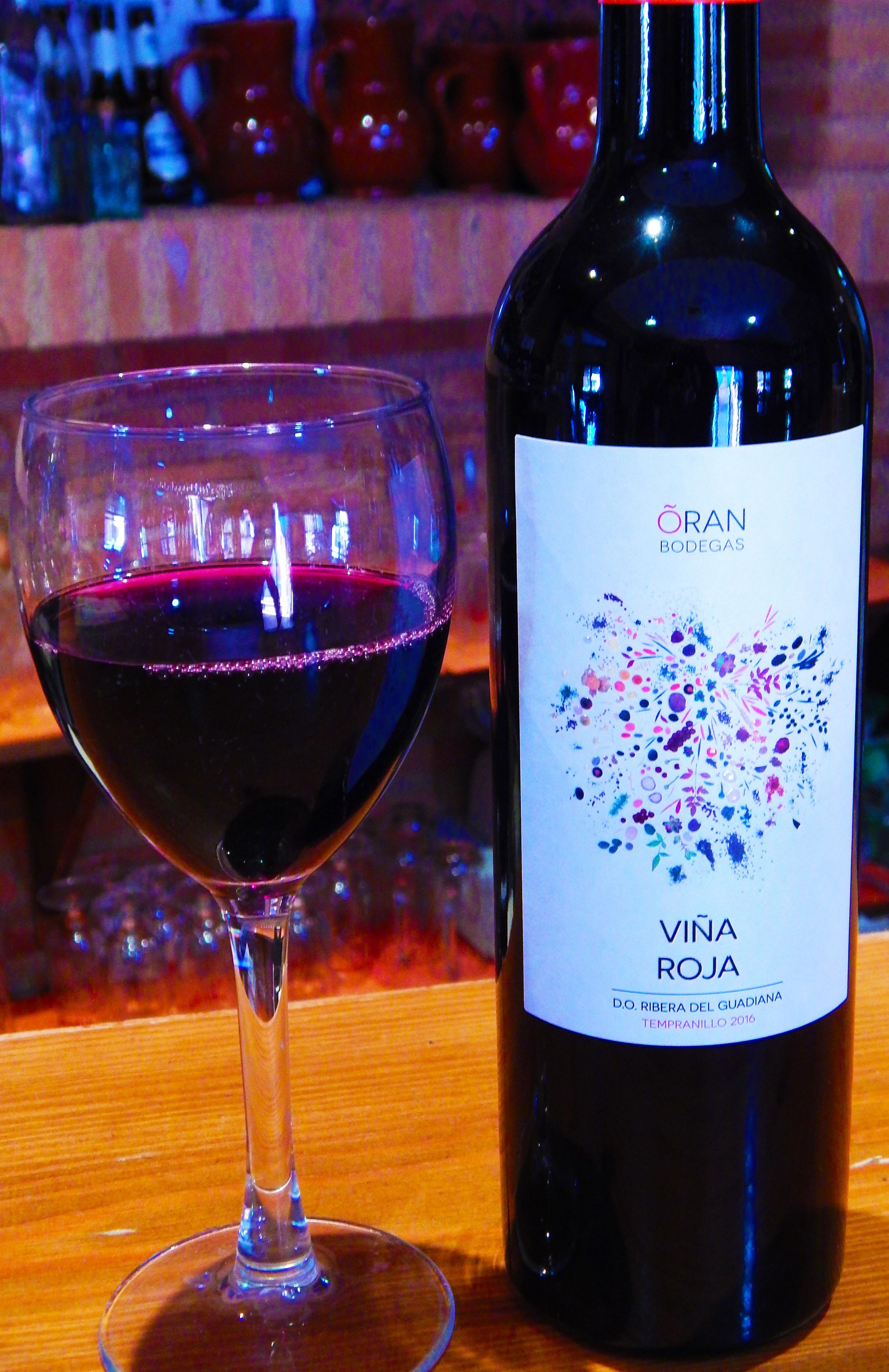 Una botella de vino Vina Roja junto a una copa llena del mismo vino.