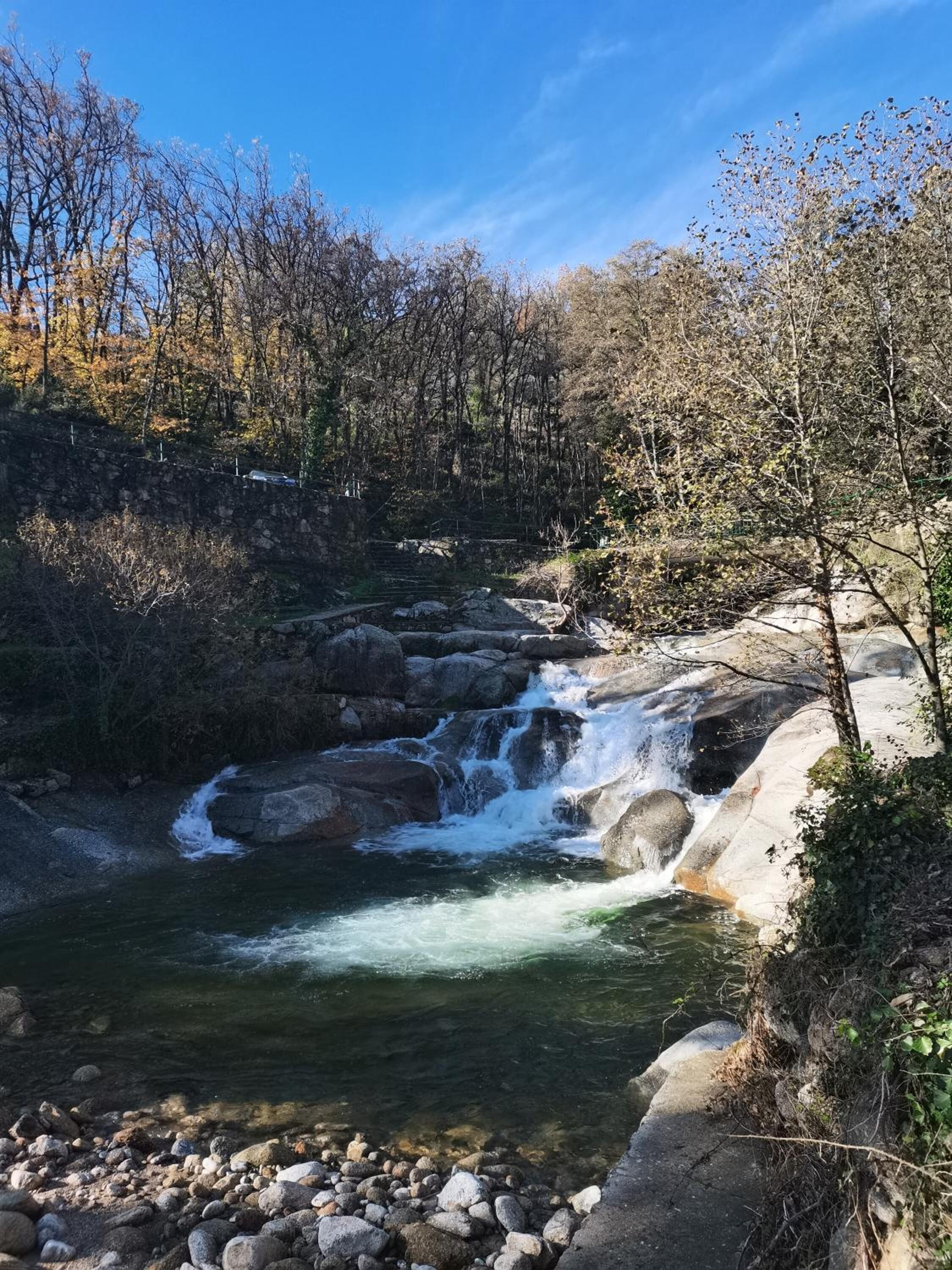 A natural landscape with a flowing river, rocky terrain, and trees.
