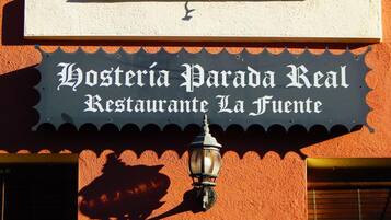 En restaurangskylt med namnet ”Hostería Parada Real Restaurante La Fuente” på en vägg med en tydlig struktur.