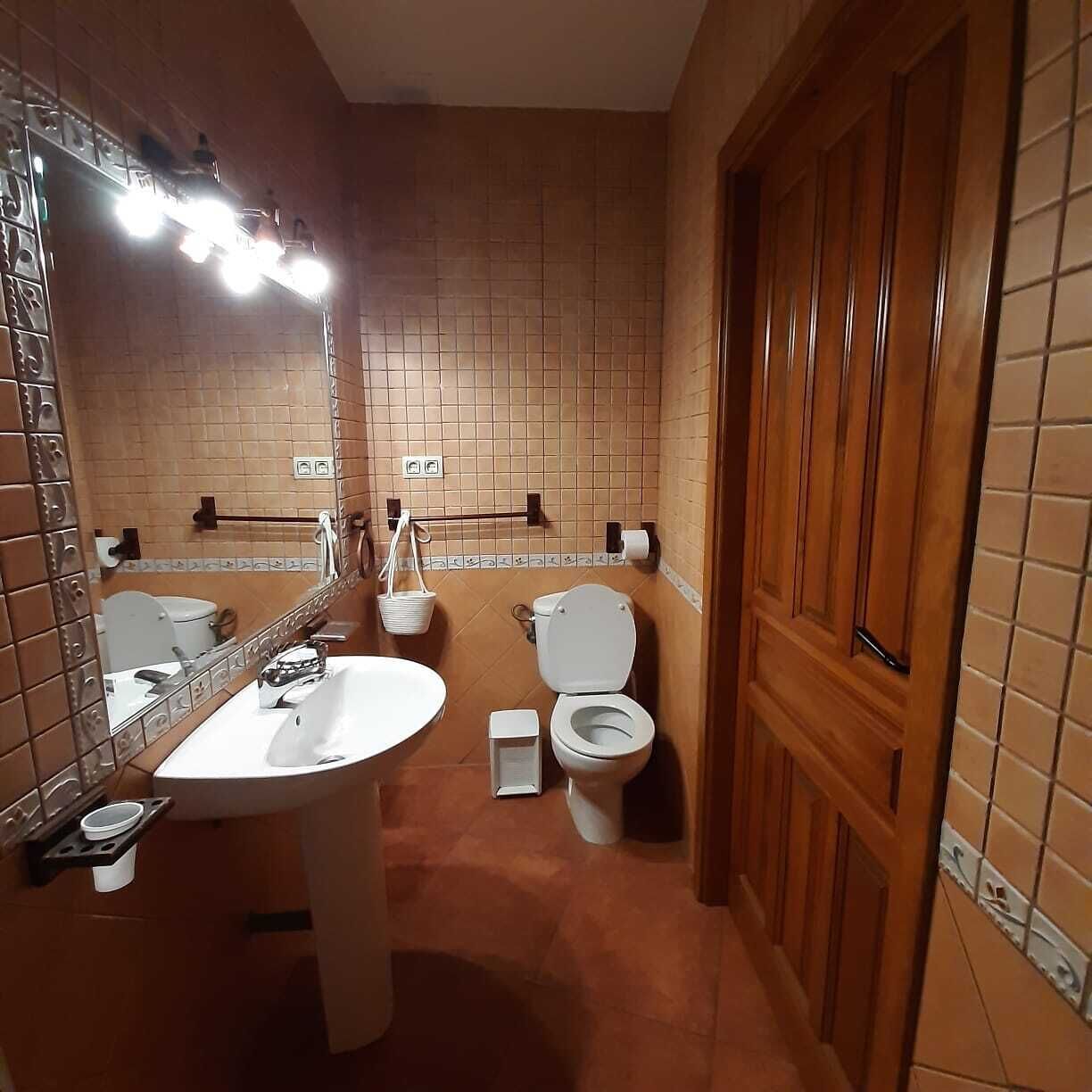 Un baño con lavamanos, espejo y dos inodoros.