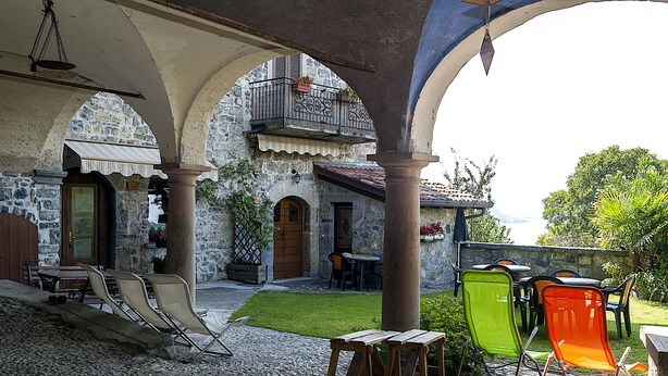 A courtyard with stone walls, a wooden table, and chairs. - Castello di Zorzino (Riva di Solto)