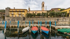 A harbor with boats docked, a clock tower, and buildings with balconies. - Castello di Zorzino (Riva di Solto)