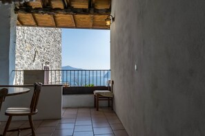 Un balcon avec un mur en pierre, une table en bois et deux chaises.