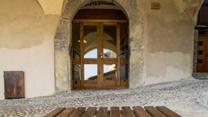 An arched doorway with a wooden door, a stone wall, and a cobblestone floor. - Castello di Zorzino (Riva di Solto)