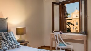 A bedroom with a bed, a desk, a chair, and a window with a view of a building. - Casa Irene (Chania)